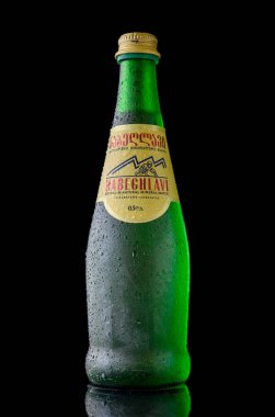 Tiflis, Gürcistan 12.11.2025 Donmuş bir şişe Nabeghlavi doğal karbonatlı sodyum bikarbonat mineral suyu, koyu siyah arka planda ince yoğunlaşma damlacıklarıyla kaplı..