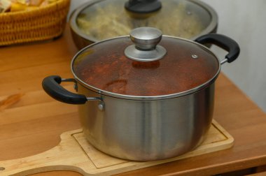 Birkaç tencere ve tava bir yemek masasında yeni pişmiş bulaşıklarla dolu. Sıcak, davetkar bir aile yemeği atmosferi yakalar. Ev yapımı yemekler servis edilmeye hazırdır..