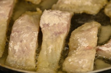 Lezzetli tilapia fileto parçaları sıcak tavada mükemmel bir altın-kahverengiye kızartılıyor. Evde taze balık pişirmenin cezbedici aromasını ve basit zevkini yakalar..