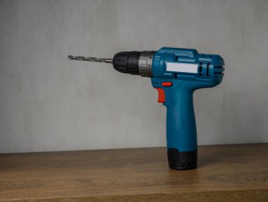 Kablosuz matkap ucu dikey olarak kırsal ahşap atölye masasında duruyor. DIY veya profesyonel konsept için kullanıma hazır araç fotoğrafçılığı.