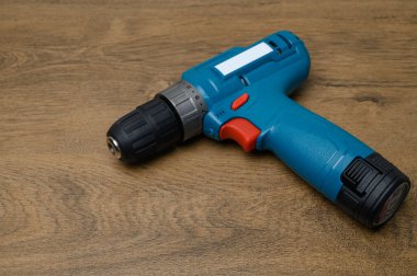 Kablosuz matkap ve kısmen çıkarılmış pil kablosuz tahta masa yüzeyinde duruyor. Pil mekanizması ve tasarım detaylarını gösteren araç fotoğrafçılığı.