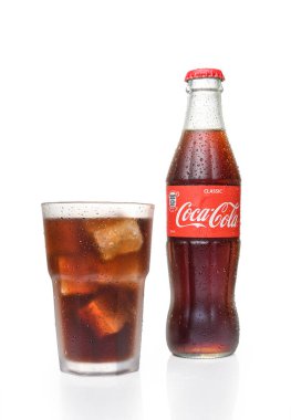 Tbilisi, Georgia 12.15.2025 conic glass bottle of Coca-Cola Classic alongside a glass filled with the carbonated beverage, isolated on pure white background. Classic soda brand photography.