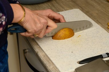 Keskin bir bıçağın patatesin etini kestiği anı yakalayan ultra yakın çekim fotoğrafçılığı beyaz kesme tahtasındaki iç dokuyu ortaya çıkarıyor..