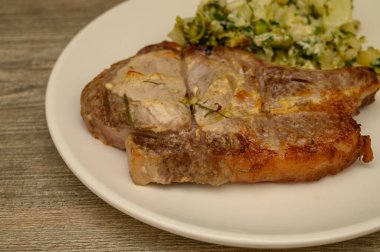 Kızarmış ya da patates püresi ve taze otlarla servis edilen sulu kemikli domuz pirzolası. Yürekli yemek sunumu fotoğrafçılık.