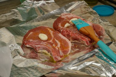 İki kemikli domuz filetosu kremalı bitki salamurası ve taze biberiye ile kaplanmış, fırın pişirme ve ızgaradan önce alüminyum folyo üzerine dizilmiş. Yemek hazırlama fotoğrafçılığı.