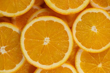 Taze dilimlenmiş portakal dilimlerinin makro görüntüsü, canlı ve dokulu bir arka plan oluşturur. Odak noktası sulu et, parlak renk ve turunçgillerin doğal deseni..