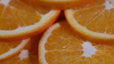 Pürüzsüz, soyut bir 4K video klipte taze turuncu dilimler koyu bir dönen yüzey üzerinde mükemmel bir daire şeklinde dönüyorlar. Doğrudan yukarıdan çekilen bu döngü, canlı renkler ve doğal desenlerle büyüleyici, kaleydoskopik bir etki yaratıyor..