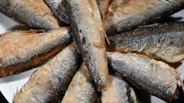 Genel olarak Kıbrıs 'ta Marida olarak bilinen kızarmış küçük balığın yukarıdan aşağı makro görüntüsü basit bir tabağa yerleştirilmiştir. Tabak yavaşça dönüyor, iştah açıcı altın-kahverengi dokular, çıtır çıtır kuyruklar ve hassas şekiller sergiliyor..