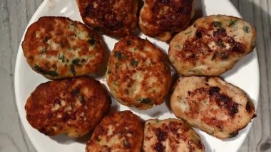 Tertemiz bir 4K video döngüsü, ev yapımı altın-kahverengi tavuk köfteleri seramik bir tabakta yavaş yavaş dönüyor, yukarıdan aşağıya doğru bir perspektiften çekiliyor. Bu klip iştah açıcı dokuyu, çıtır çıtır kenarları vurgular.