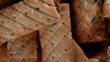 Kuru üzümlerle süslenmiş, seramik bir tabakta yavaşça dönen narin, pürüzsüz pofuduk kurabiyelerden oluşan kusursuz bir 4K video döngüsü. Yukarıdan aşağıya doğru çekimde pastanın altın-kahverengi, katmanlı dokusu vurgulanıyor.