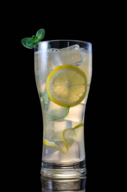 Ezilmiş buz ve parlak nane yapraklarıyla dolu, zengin siyah bir zemin üzerinde izole edilmiş gevrek, soğuk bir mojito camı. Görüntü içkinin canlandırıcı karakterini ve görsel berraklığını vurgular..