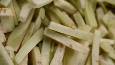 Kızartma için taze kesilmiş çiğ patlıcan jülyen çubukları tahta bir kesme tahtasının üzerinde döner. Yemek hazırlama, doku ve canlı mor-beyaz renkleri gösterir.