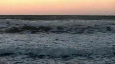 Kuzey Kıbrıs üzerinde kasvetli fırtınalı gün batımı. Kara bulutlar, dalgalar ve deniz üzerindeki ışık demetleri. Dramatik projeler için destansı ve sinematik manzara.