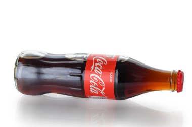 Tiflis, Gürcistan 11.20.2025. İkonik Coca-Cola cam şişesi kendine özgü dış hatlarıyla beyaz arka planda güzelce sunuluyor. Ferahlatıcı ve zamansız marka tasarımı mükemmelliğinin sembolü..