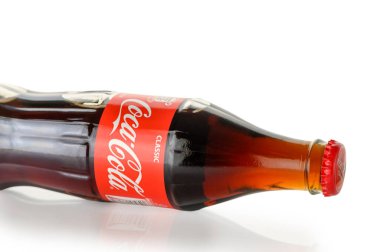 Tiflis, Gürcistan 11.20.2025. Klasik bir Coca-Cola şişesi saf beyaz arka planda zarif bir şekilde sergilenir. İkonik şekillendirilmiş şişede markanın zamansız tasarımı ve canlandırıcı içeceği sergileniyor..