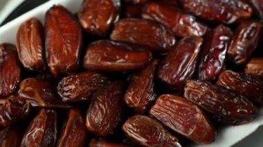 Büyüleyici derecede yakın plan kurumuş hurma dönüşümlü, karmaşık buruşuk deri dokusunu, doğal çatlakları ve yapışkan parlatıcılarını ortaya çıkarıyor. Sıcak kehribar tonları ve organik desenler güzel bir soyut kompozisyon oluşturur..