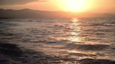 Günbatımı gökyüzü, Kıbrıs kıyısı boyunca uzanan sakin Akdeniz 'de aynı renk darbelerini resmediyor. Mükemmel bir ayna, basit bir çift doğal tuval..