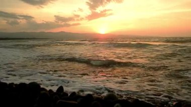 Kuzey Kıbrıs 'ın Gaziveren Akdeniz kıyı şeridi üzerinde dramatik kırmızı gün batımı. Altın saat yansımaları Morphou Körfezi kıyılarında.