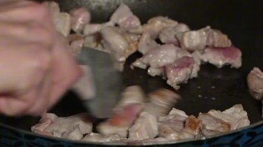 Domuz parçaları soğanlı tavada kızartılıyor. Sulu et parçaları cızırdıyor, ev yapımı yemek pişiriyor..