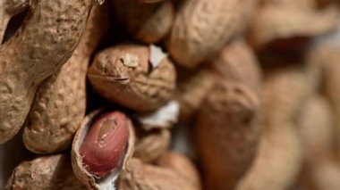 Yüksek hızda dönen tek bir fıstık kabuğunun aşırı yakın plan görüntüsü, kuru, kırılgan kabuğunun parçaları parçalanıyor ve siyah bir zemine doğru uçuyor. Yüksek hızlı bir fotoğraf çekimi, bir yıkım anını yakalıyor.