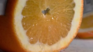 Beyaz üniformalı profesyonel şef, ahşap bir kesme tahtasındaki taze ve sulu portakalı dilimlemek için keskin bir mutfak bıçağı kullanır. Citrus suyu püskürtüyor, bir dilim kesiliyor. Ellerine, bıçağına ve parlak turuncu etine yakından bak..