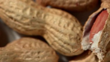 Kabuklu, dokulu kabuklarındaki, pürüzsüz, karanlık bir yüzey üzerinde dönen ve dönen bir sürü fıstığın yukarıdan aşağı görüntüsü. Dinamik, biraz bulanık hareket bir enerji ve doğal hareket hissi yaratır. Eşsiz şekle ve toprağa odaklan.