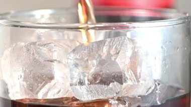 Coca Cola buz küpleriyle dolu bir bardağa dolduruluyor. Karbonatlı içecek, yavaş çekim yakın çekim..