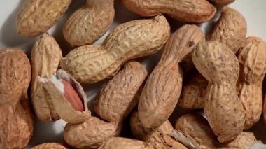 Güneşli, ahşap bir yüzey üzerinde dönen ve dönen desenli kabuklarındaki tüm fıstıkları tepeden çekiyorlar. Doğal, nazik hareket, sıcak ahşap taneciklere karşı organik formları ve kabukların kırsal dokusunu vurgular. Kavram