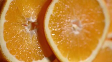 Ağır çekimde dönen olgun portakal dilimlerinin aşırı yakın çekimi. Turunçgil dokusunun detaylı görüntüsü, parlayan posa ve taze meyve suyu. Kabuktaki su damlacıkları tazelik kavramını geliştirir. Susuzluk için mükemmel.,