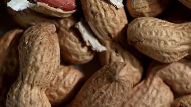 Doğal kabuklarındaki taze çiğ fıstıklar karanlık bir arka planda yavaşça dönüyorlar. Dokulu fıstık kabuğu, organik işlenmemiş fındık, sağlıklı atıştırmalık konsepti. Pürüzsüz 360 derece dönüş, makro detay, 4K.