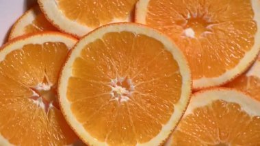 Ağır çekimde dönen olgun portakal dilimlerinin aşırı yakın çekimi. Turunçgil dokusunun detaylı görüntüsü, parlayan posa ve taze meyve suyu. Kabuktaki su damlacıkları tazelik kavramını geliştirir. Susuzluk, yaz içeceği ve organik yiyecekler için mükemmel.,