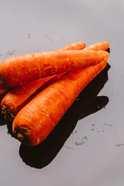 Friske rå gulerødder på sort baggrund - Stock-foto