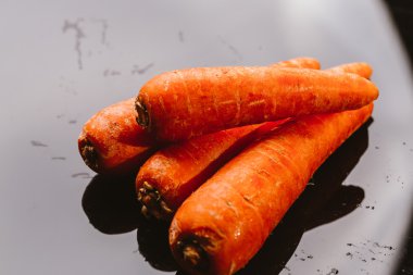 Siyah bir zemin üzerine taze çiğ havuç