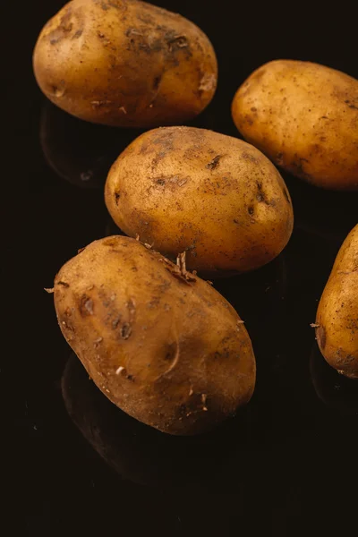 Verse rauwe aardappelen op een zwarte achtergrond — Stockfoto