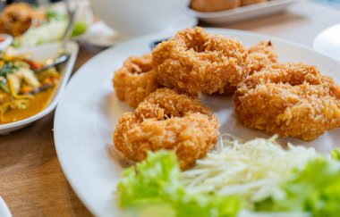 Beyaz bir tabakta kıyılmış lahana ve marullu kızarmış karides kekleri..