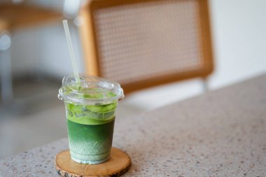 Plastik bardakta buzlu kibrit latte açık ahşap bir masada oturur..