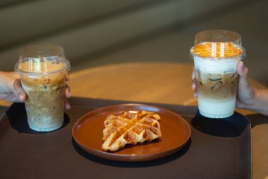 Buzlu kahve içen, bir kafede tepside servis edilen waffle yapan insanlar..