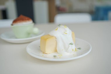 Krem şantili kremalı ve küçük beyaz bir tabakta lezzetli bir tatlıya yakın plan..