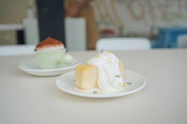 Krem şantili kremalı ve küçük beyaz bir tabakta lezzetli bir tatlıya yakın plan..