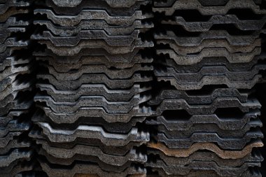 Yığılmış koyu gri kiremitler desenli, tekrarlı ve kıvrımlı desenler oluşturuyor..