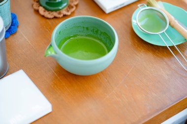 Durgun bir hayat, ahşap bir masada kibrit yeşil çay yapmak için geleneksel çatal bıçakları gösterir. 