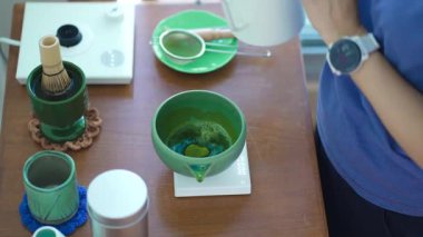 Eller tören hazırlıyor çırpı, kase ve elektrikli su ısıtıcısı ile kibrit yeşil çayı.