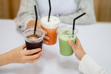 Üç el farklı renkte soğuk içeceklerle plastik bardaklarda kadeh kaldırıyor..