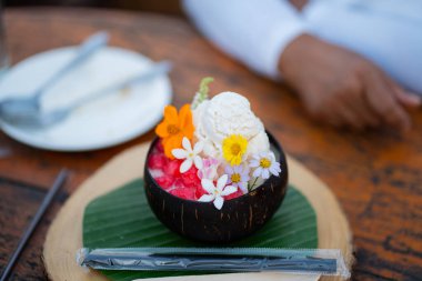 Lezzetli tatlı hindistan cevizli mus, ananas kompostosu ve yenilebilir çiçeklerle süslenir.
