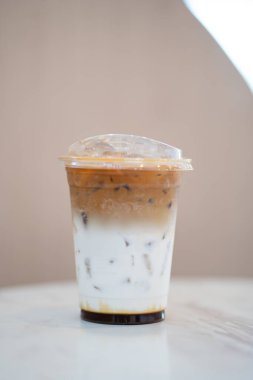Plastik bardakta buzlu kahve. Kafe ortamındaki mermer masada..