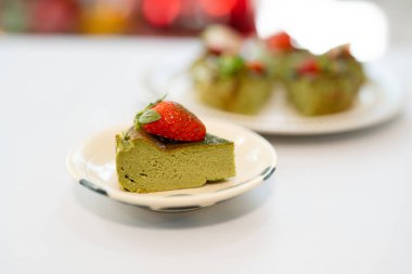 Üçgen dilimli yeşil kibrit peynirli kek üzerine de taze çilek.