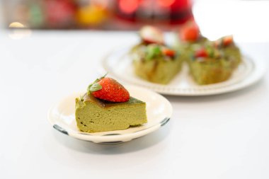 Üçgen dilimli yeşil kibrit peynirli kek üzerine de taze çilek.