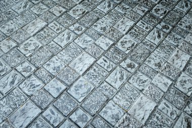 Birçok açık gri dikdörtgen taş karolar geniş bir açık zemin yüzeyi boyunca çapraz olarak düzenlenmiştir, yıpranmış dokuları ve koyu harç hatlarını göstermektedir..