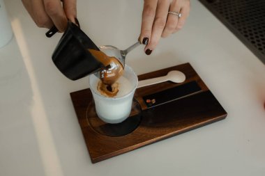 Bardağa soğuk taze süt döken bir kadın baristanın yakın çekimi. Sürecin Kirli Latte Kahve Kremalı Kupasını Yapması
