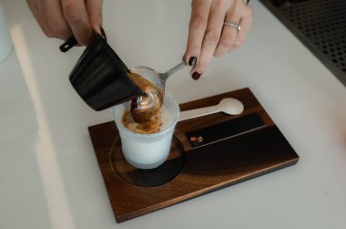 Bardağa soğuk taze süt döken bir kadın baristanın yakın çekimi. Sürecin Kirli Latte Kahve Kremalı Kupasını Yapması